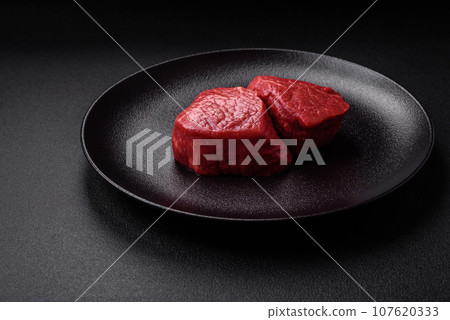 Fresh juicy raw beef medallions with salt and spices Fresh juicy raw beef medallions with salt and spices 107620333