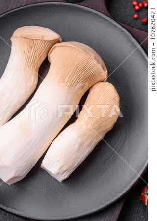 Pleurotus eryngii mushrooms on a dark concrete background Pleurotus eryngii mushrooms on a dark concrete background 107620421