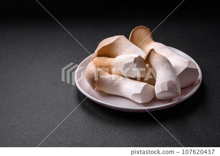 Pleurotus eryngii mushrooms on a dark concrete background 107620437