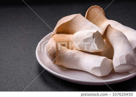 Pleurotus eryngii mushrooms on a dark concrete background 107620450