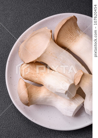 Pleurotus eryngii mushrooms on a dark concrete background 107620454