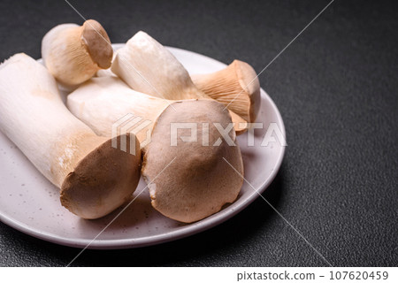 Pleurotus eryngii mushrooms on a dark concrete background Pleurotus eryngii mushrooms on a dark concrete background 107620459