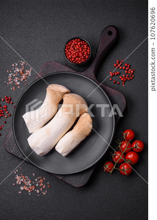 Pleurotus eryngii mushrooms on a dark concrete background Pleurotus eryngii mushrooms on a dark concrete background 107620696