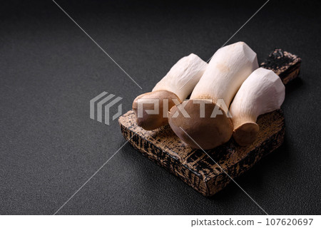 Pleurotus eryngii mushrooms on a dark concrete background Pleurotus eryngii mushrooms on a dark concrete background 107620697