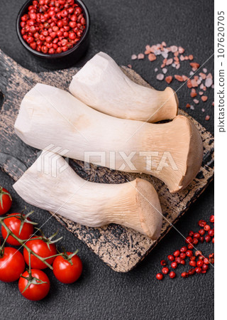 Pleurotus eryngii mushrooms on a dark concrete background 107620705