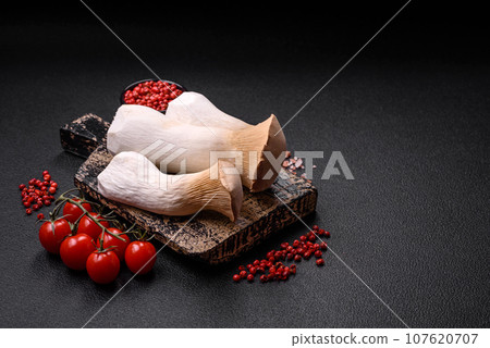 Pleurotus eryngii mushrooms on a dark concrete background 107620707