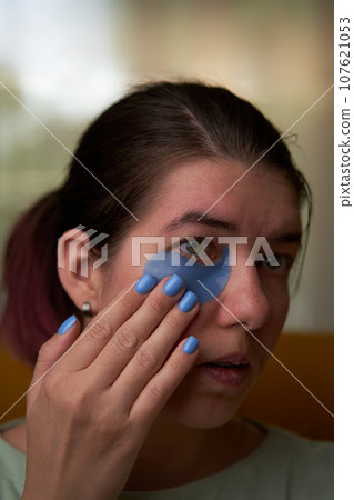 Woman is using cosmetic patches on face. 107621053