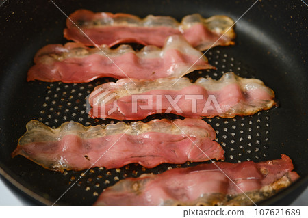 Frying bacon in a frying pan Frying bacon in a frying pan 107621689