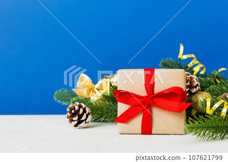 New Year Christmas mood, gift box, branches of a christmas tree, New Year decorations on a colored background New Year Christmas mood, gift box, branches of a christmas tree, New Year decorations on a colored background 107621799
