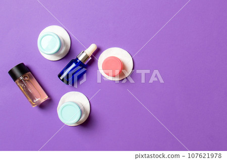 Set of travel size cosmetic bottles on colored background. Flat lay of cream jars. Top view of bodycare style concept 107621978