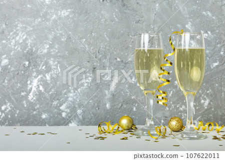 Champagne glasses and christmas decor on colored holiday background. Flat lay New Year decorations 107622011