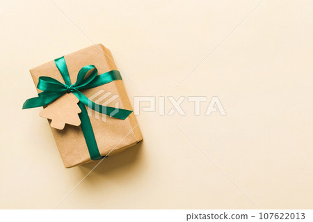 wrapped christmas or other holiday handmade present in paper with colored ribbon. Present box, decoration of gift on colourfull table, top view with copy space 107622013