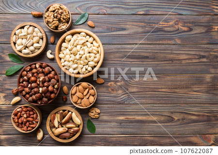 mixed nuts in wooden bowl. Mix of various nuts on colored background. pistachios, cashews, walnuts, hazelnuts, peanuts and brazil nuts 107622087