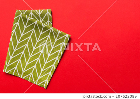 top view with green kitchen napkin isolated on table background. Folded cloth for mockup with copy space, Flat lay. Minimal style 107622089