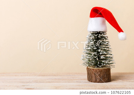 One small Christmas tree with santa hat on colored background. new year decoration with copy space 107622105
