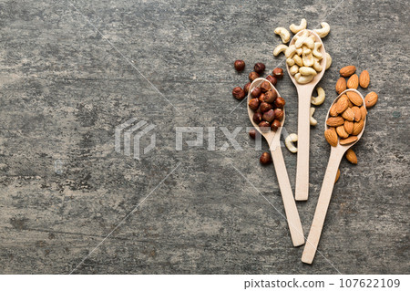 Assortment of nuts in wooden spoon on colored table. Cashew, hazelnuts, walnuts, almonds. Mix of nuts Top view with copy space 107622109