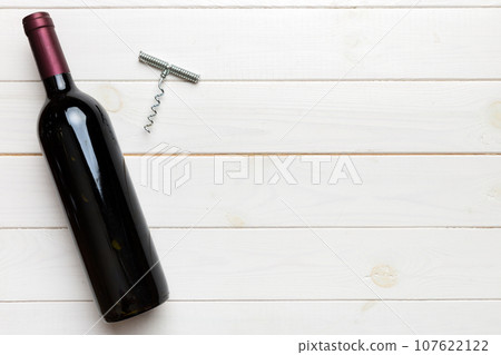 One Bottle of red wine with corkscrew on colored table. Flat lay, top view wth copy space 107622122