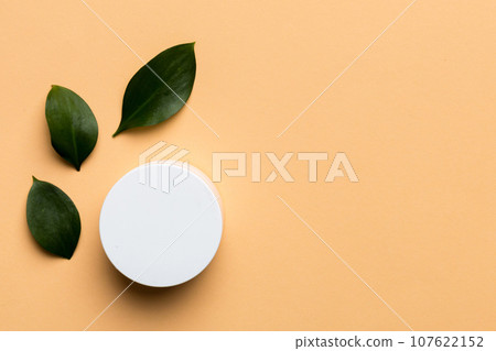 Organic cosmetic product with green leaves on color background. Copy space, flat lay 107622152