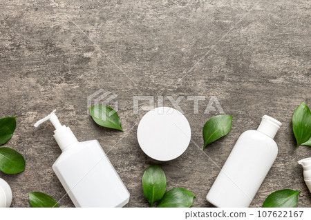 Organic cosmetic products with green leaves on cement background. Copy space, flat lay Organic cosmetic products with green leaves on cement background. Copy space, flat lay 107622167