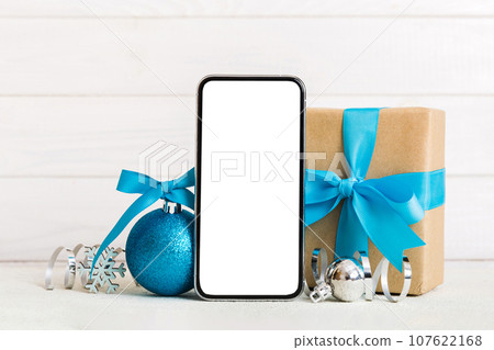 Digital phone mock up with rustic Christmas decorations for app presentation with empty space for you design. Christmas online shopping concept. Tablet with copy space on colored background Digital phone mock up with rustic Christmas decorations for app presentation with empty space for you design. Christmas online shopping concept. Tablet with copy space on colored background 107622168