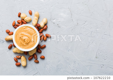 Bowl of peanut butter and peanuts on table background. top view with copy space. Creamy peanut pasta in small bowl Bowl of peanut butter and peanuts on table background. top view with copy space. Creamy peanut pasta in small bowl 107622210