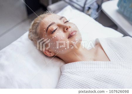 A young attractive blonde was put cream on her face. 107626098