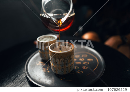 Black coffee is being poured into a ceramic mug. 107626229