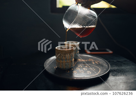 Black coffee is being poured into a ceramic mug. Black coffee is being poured into a ceramic mug. 107626236