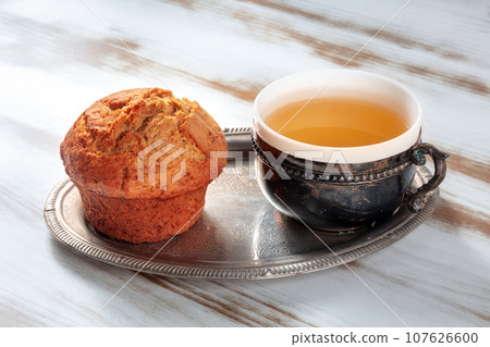 Orange muffin with tea on a rustic wooden kitchen table 107626600