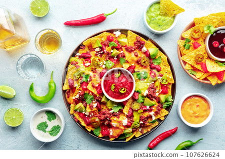 Loaded nachos. Mexican nacho chips with beef, overhead flat lay shot Loaded nachos. Mexican nacho chips with beef, overhead flat lay shot 107626624