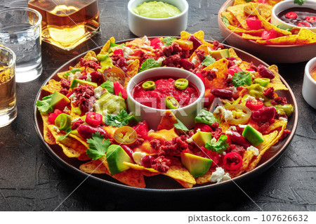 Loaded nachos. Mexican nacho chips with beef, with guacamole sauce Loaded nachos. Mexican nacho chips with beef, with guacamole sauce 107626632