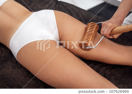 Massage madera. Maderotherapy anti cellulite massage treatment with wooden prop Massage madera. Maderotherapy anti cellulite massage treatment with wooden prop 107626900