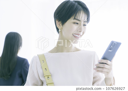 Portrait of a smiling young woman looking at smartphone Portrait of a smiling young woman looking at smartphone 107626927
