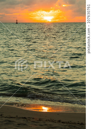 Sandy beach illuminated by the setting sun 107630761