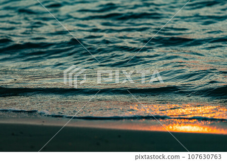 Sandy beach illuminated by the setting sun 107630763