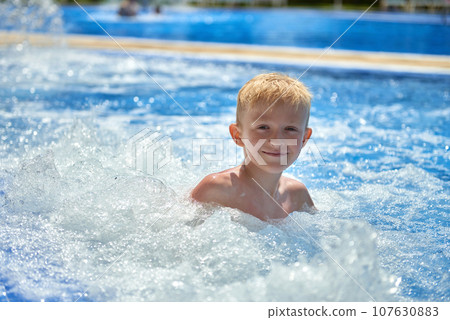 Young boy kid child eight years old splashing in swimming pool having fun leisure activity. Boy happy swimming in a pool. Activities on the pool, children swimming and playing in water, happiness and Young boy kid child eight years old splashing in swimming pool having fun leisure activity. Boy happy swimming in a pool. Activities on the pool, children swimming and playing in water, happiness and 107630883