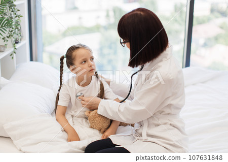 Female medic using stethoscope for sick girl checkup 107631848