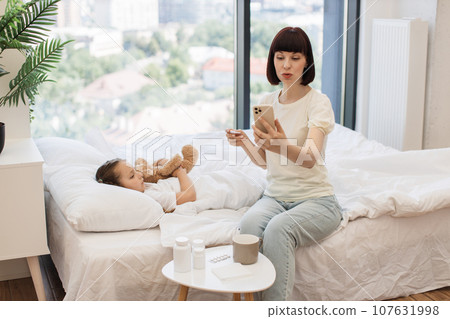 Mother having video call with doctor while treating ill kid Mother having video call with doctor while treating ill kid 107631998