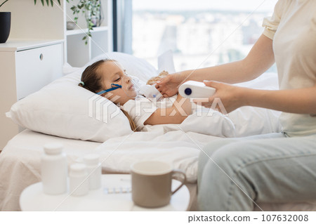 Sick girl inhaling mist from nebulizer with help of mother Sick girl inhaling mist from nebulizer with help of mother 107632008
