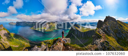 Hiker standing on the top of Husfjellet Mountain on Senja Island in Norway Hiker standing on the top of Husfjellet Mountain on Senja Island in Norway 107632060