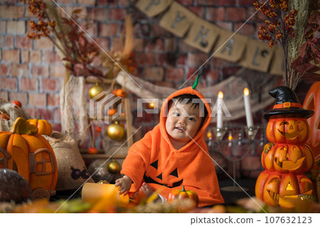 An 11-month-old baby smiles happily surrounded by a Halloween photo set in October. An 11-month-old baby smiles happily surrounded by a Halloween photo set in October. 107632123