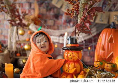 An 11-month-old baby smiles happily surrounded by a Halloween photo set in October. An 11-month-old baby smiles happily surrounded by a Halloween photo set in October. 107632136