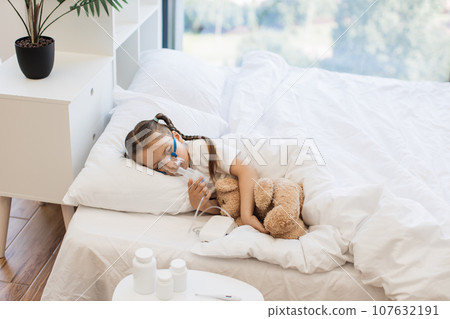 Pretty ill girl inhaling medication through nebulizer 107632191