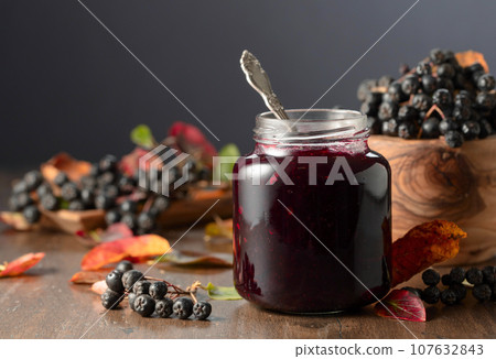 Chokeberry jam and fresh berries on an old wooden table. 107632843