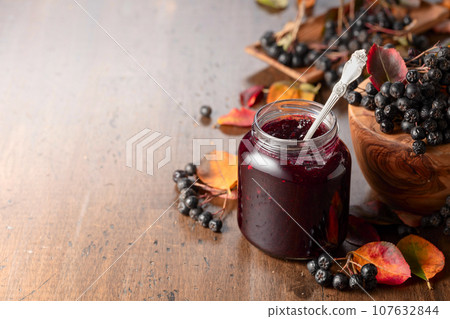 Chokeberry jam and fresh berries on an old wooden table. 107632844