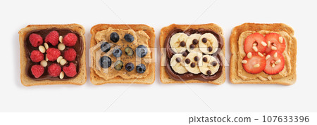 Sweet toasts with raspberries, banana, strawberries, blueberries on light background. Flatly. Sweet toasts with raspberries, banana, strawberries, blueberries on light background. Flatly. 107633396