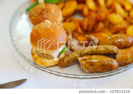 Mini burgers on a plate with french fries and sausages.  107633528