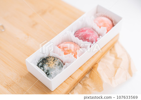 Appetizing colored mochi in a box on a wooden board Appetizing colored mochi in a box on a wooden board 107633569