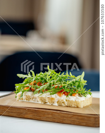 Tasty bruschetta with salmon and arugula on restaurant table in interior 107633580
