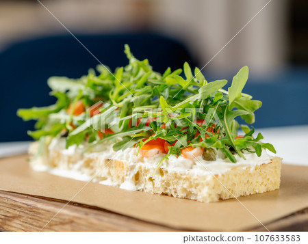 Tasty bruschetta with salmon and arugula on restaurant table in interior 107633583
